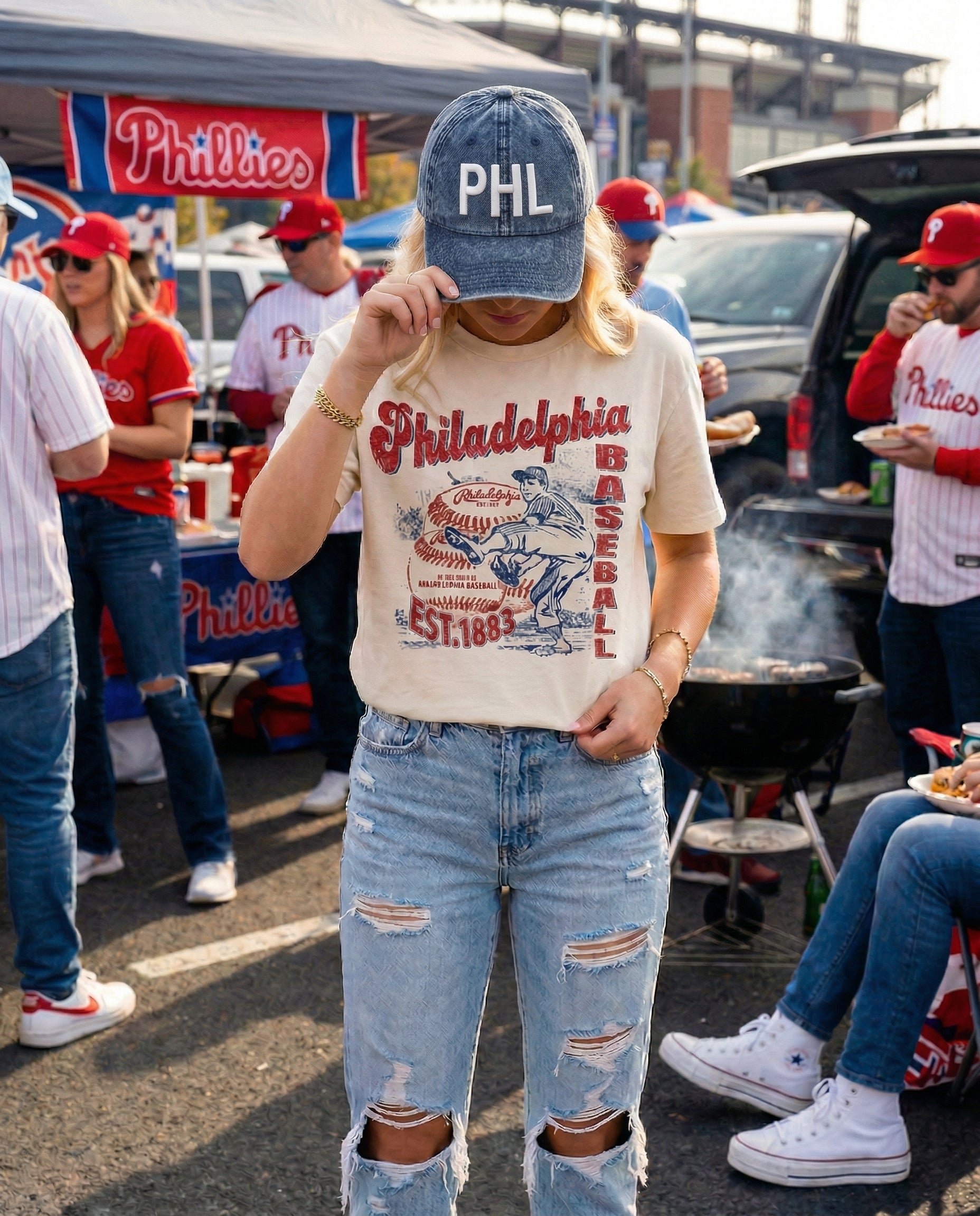 Person wearing a 'PHL' cap and 'Philadelphia Baseball' shirt at a sports event.