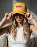 Woman wearing a yellow cap with 'Sunshine on My Mind' text, smiling against a neutral background