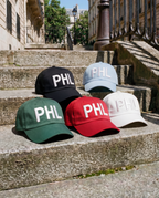 Five caps with 'PHL' on them placed on stone steps outdoors.